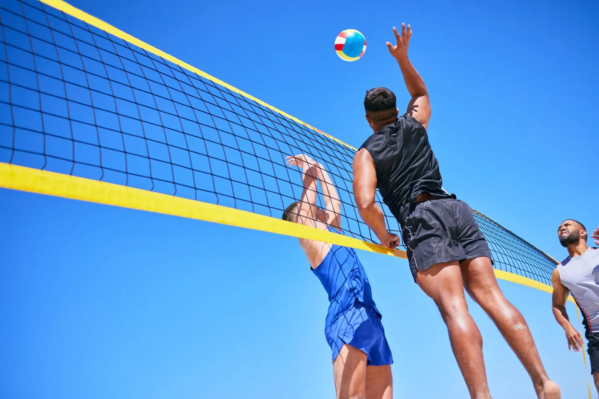 Beach volleyball players enjoying the sun, demonstrating the importance of sunscreen for active lifestyle.