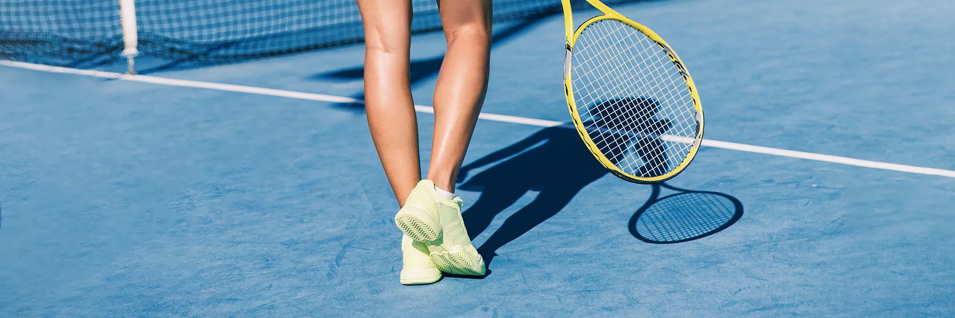 Woman with tennis racket on court, highlighting the importance of sunscreen for active lifestyle.
