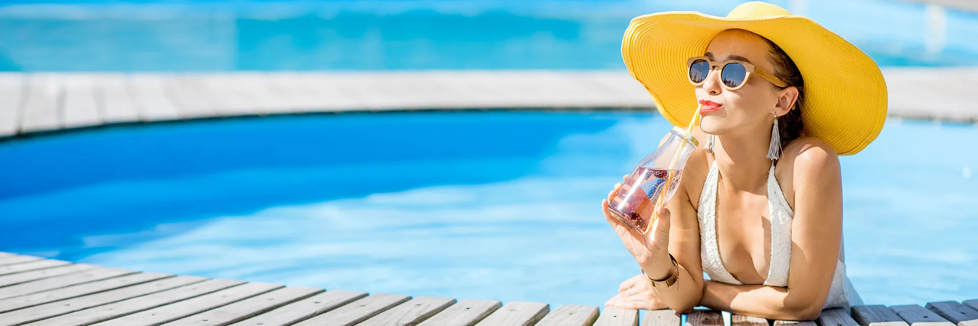 Expert opinion on SPF: Woman relaxing by the pool with sun hat and sunglasses