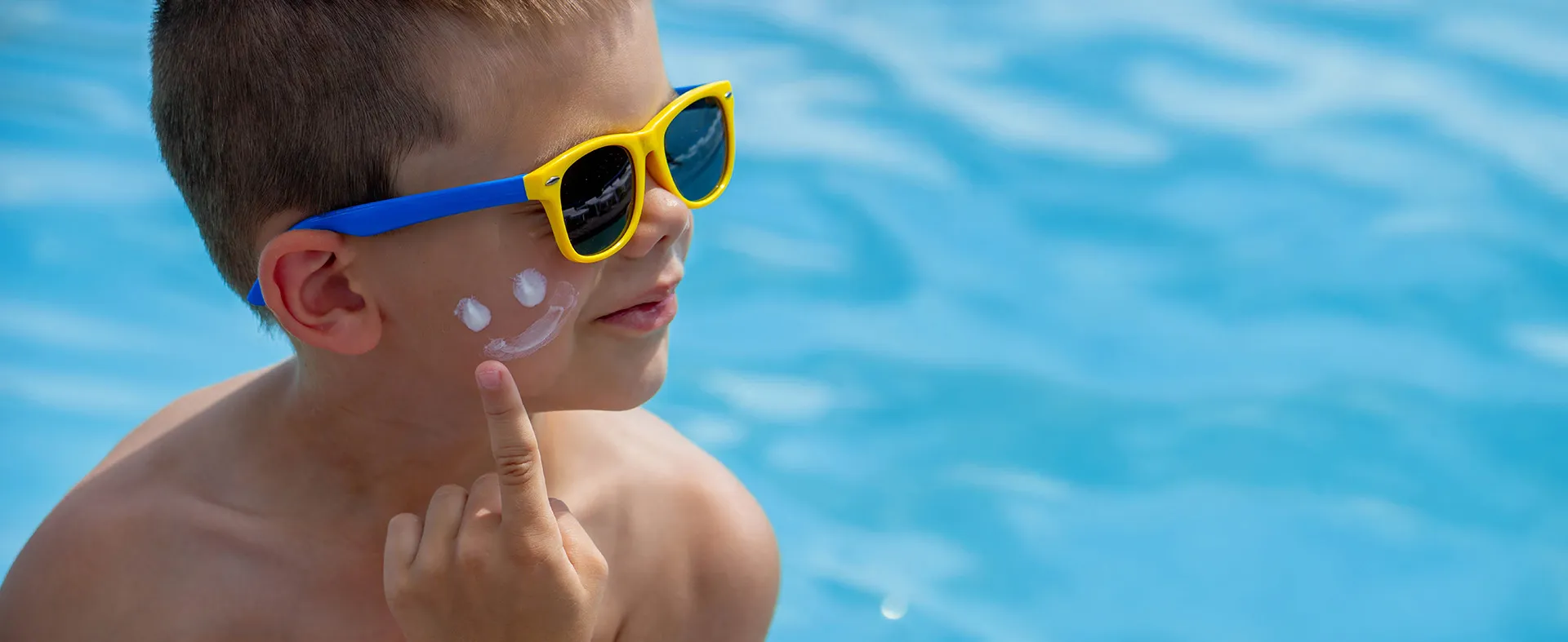 Expert opinion on SPF: Child with sunscreen and sunglasses by the pool
