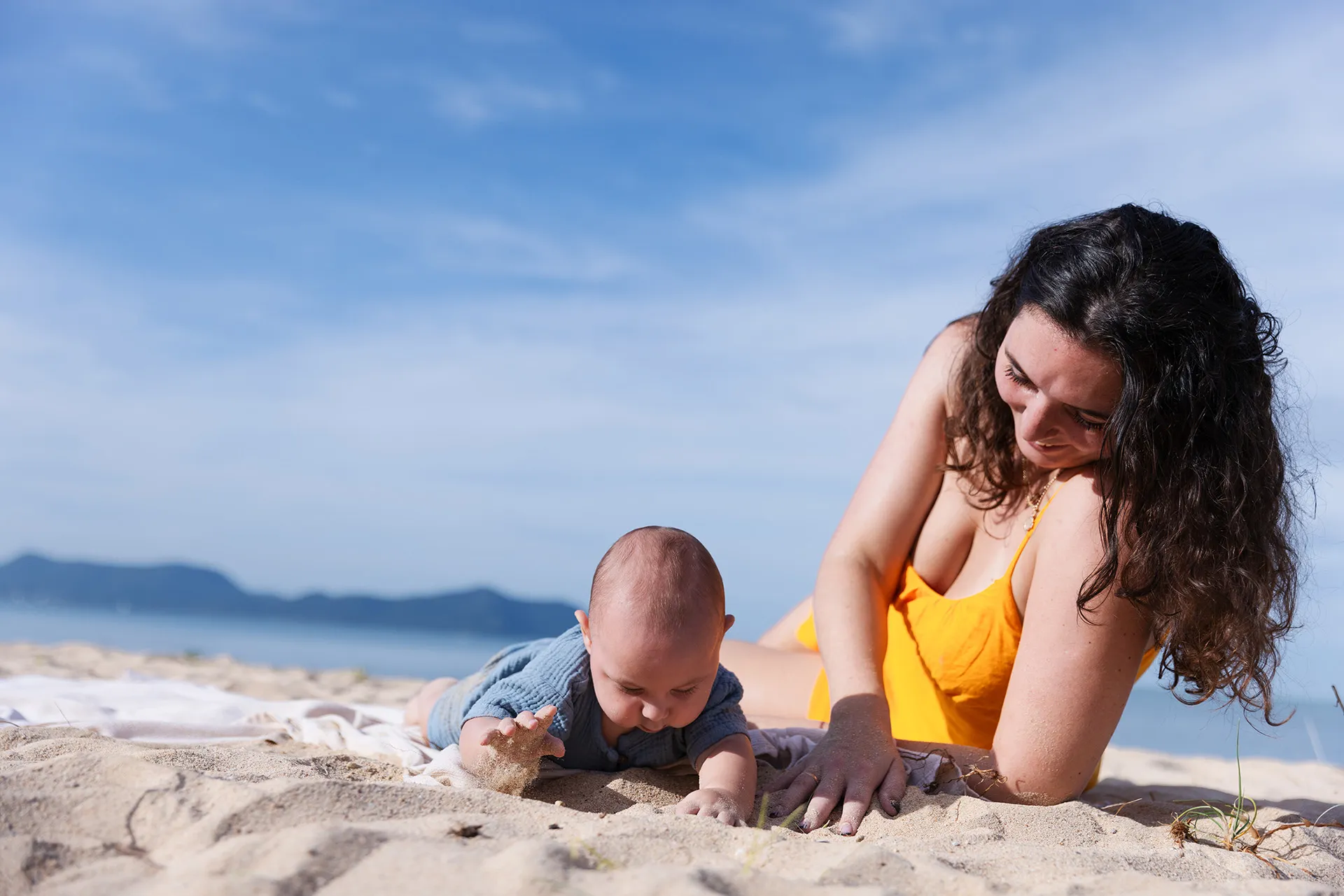 Mother and baby enjoying the beach—sun protection for babies with shade and light clothing.