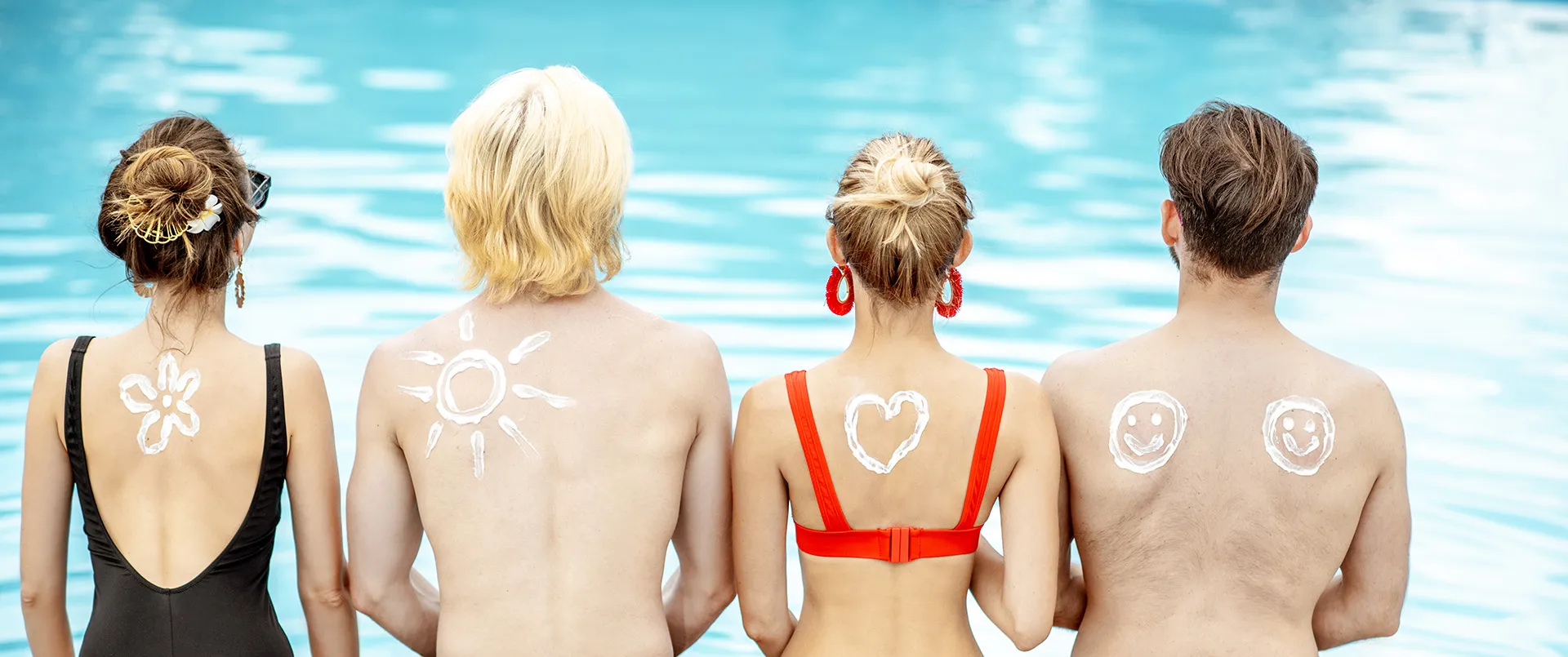 Four people by the pool with sun cream art on their backs, showing awareness of UV radiation skin cancer prevention.